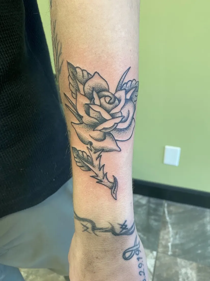 Fine-line rose tattoo on a forearm