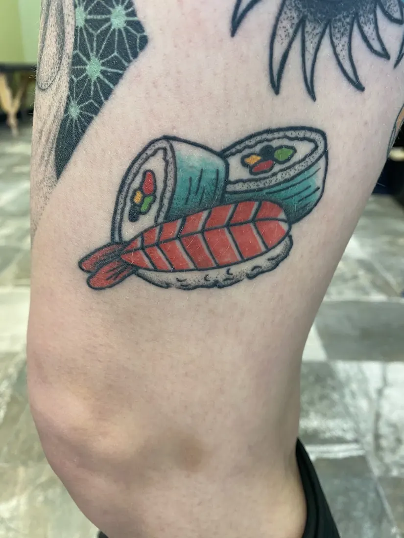 Traditional sushi roll tattoo on a thigh