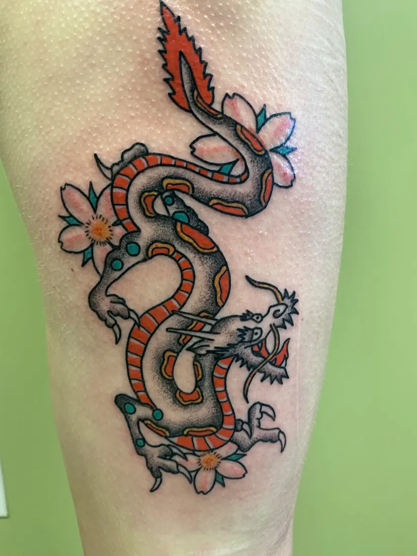 Traditional dragon and cherry-blossom tattoo on a calf